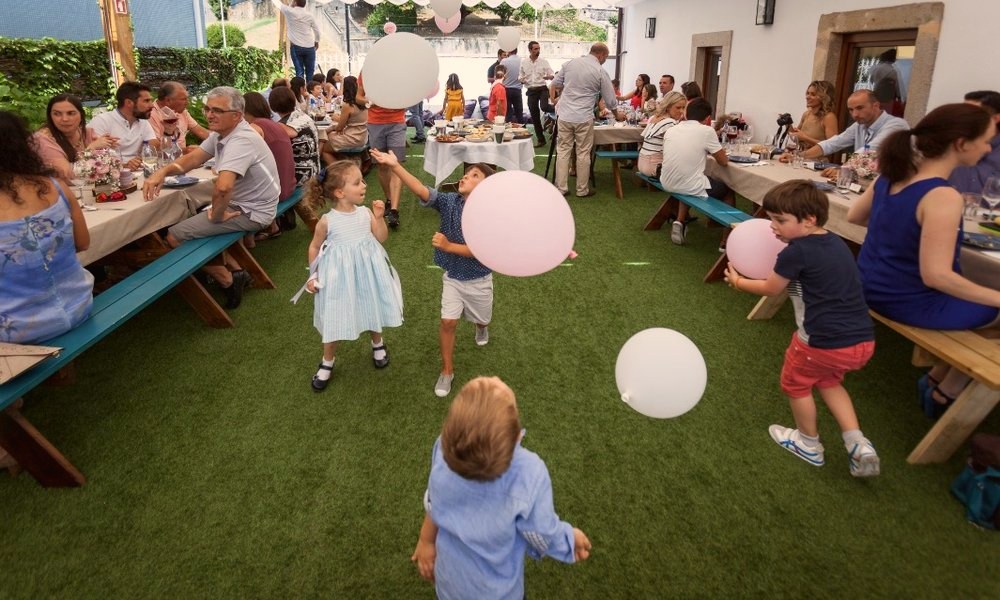 Crianças a brincar com balões entre as mesas, num batizado