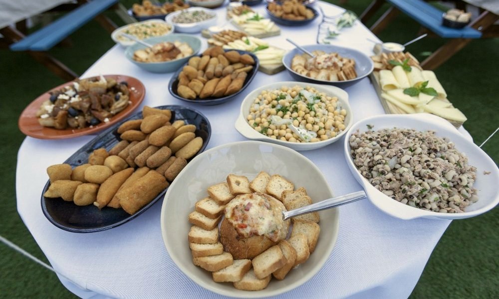 Rissóis, croquetes, saladas e queijos na mesa de entradas