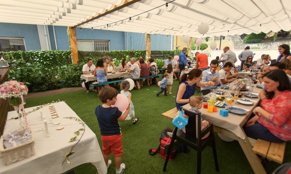 Festa de família no jardim, com mesas compridas sob o toldo